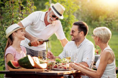 Mutlu büyük bir aile yaz aylarında bir piknik masa etrafında öğle süre having fun.