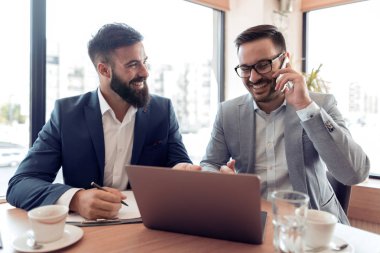 İki yakışıklı işadamları ofiste oturan bir proje üzerinde birlikte çalışma.