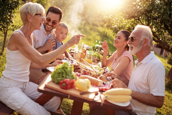 彼らは夏のピクニック テーブルを囲んで昼食中に楽しんで幸せな大家族 — ストック写真