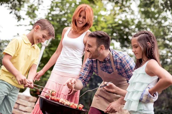 Food,people and family concept-man cooking meat on barbecue grill at summer garden party.
