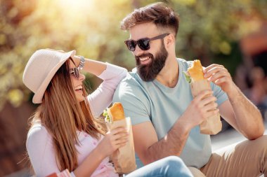 Genç çift sandviç açık havada yemek.
