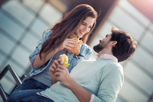 Mutlu bir çift portresi. Onlar gülüyor ve sandviç yeme ve having a büyük zaman.