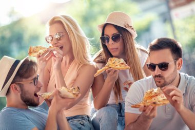 Grup neşeli arkadaşıyla parkta pizza yemek