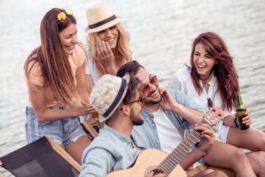 Arkadaşlar eğlenmeye sahilde gitar ile grup. Yaz, tatil, tatil, müzik ve insan kavramı.