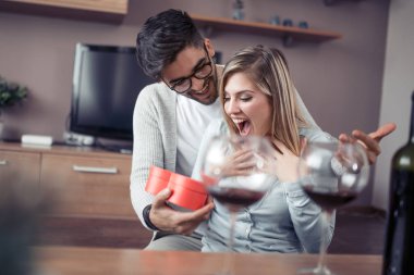 Güzel genç çift evde kutluyor. Yakışıklı adam kız arkadaşı bir hediye kutusu veren.