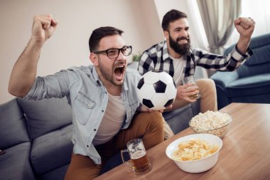 Dostluk, spor, insanlar ve eğlence kavramı - TV'de futbol evde izlerken mutlu erkek arkadaşlar.