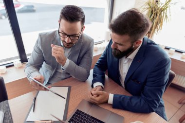 Bir gülümseme ile iki emin iş adamları kontrol iş ofiste dizüstü.