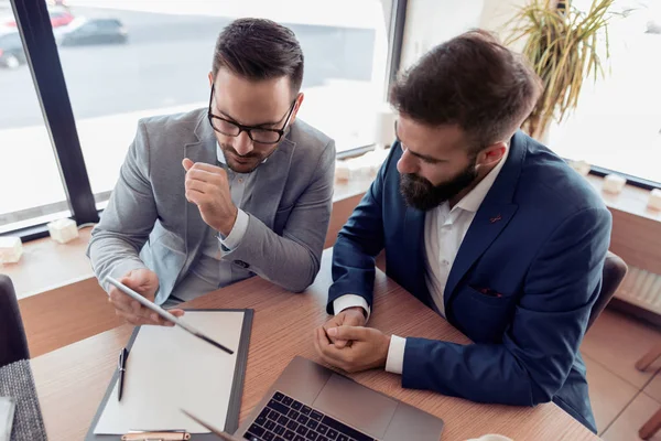 Bir gülümseme ile iki emin iş adamları kontrol iş ofiste dizüstü.