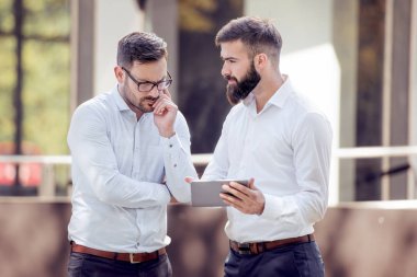 Yeni bir proje birlikte tartışıyor. Onlardan bir şey işaret ederken dijital tablet arıyorsunuz iki emin iş adamları.