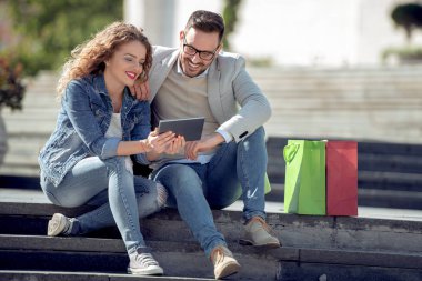 Açık havada eğleniyor ve gülümseyerek, tablet üzerinde seyir mutlu genç Çift.