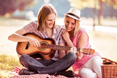 Genç adam onun kıza parkta gitar çalmak.