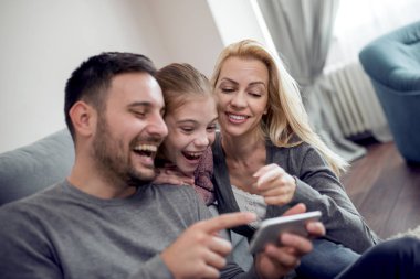 Tatil, teknoloji ve insan kavramı-mutlu aile oturma üstünde akıllı telefon evde kanepe ve alma selfie resimle.