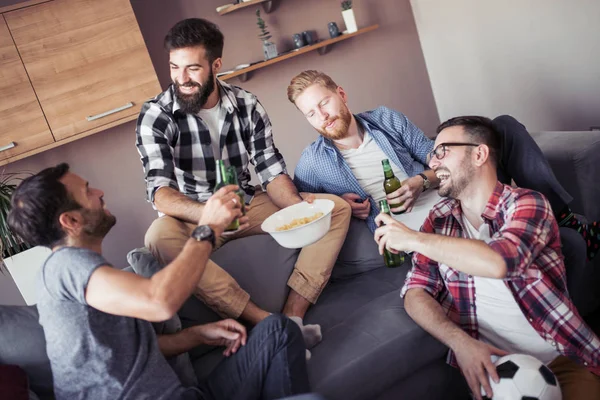 Mutlu genç arkadaşlar içki şişeleri ile dinlenme, futbol hakkında konuşuyor ve gülümseyen.