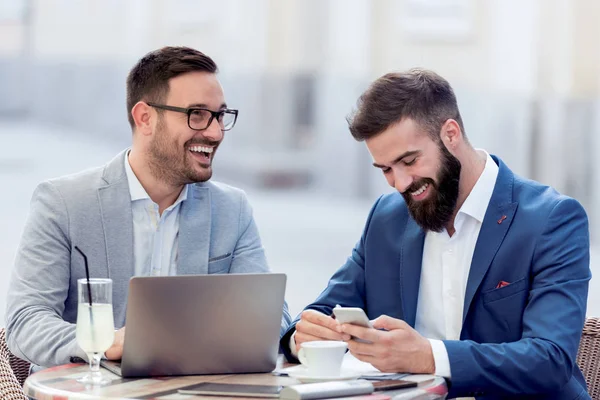 Dizüstü bilgisayarda çalışan ve birlikte kafede bir şey tartışırken iki iş adamları.
