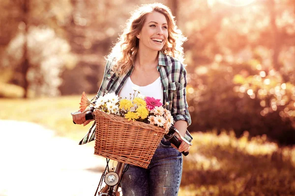日当たりの良い Dayriding 自転車で公園でバスケットの花を持つ美しい少女 — ストック写真