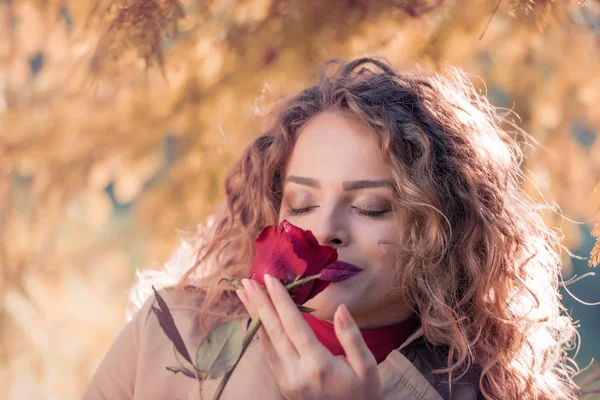Kırmızı gül ile sonbahar parkta güzel kadın.