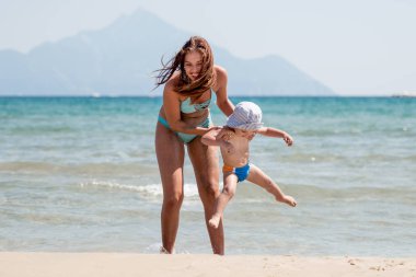 Kadın bir yürüyüş sahip ve sahilde küçük bir çocuk eğlenin.