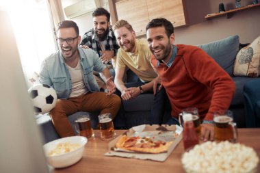 Televizyonda maç izlerken ve gol kutluyor arkadaş grubu.