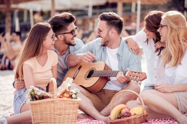 Gençlerin grup birlikte sahilde oturan ve birlikte eğlenmek mutlu.