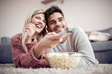 Yerde yatarken Tv izlerken, evde, patlamış mısır yemek mutlu çift.