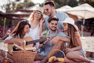 Sahilde eğleniyor ve gitar çalmak arkadaşlar 