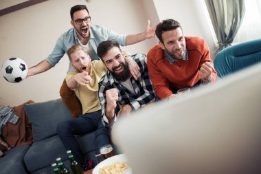 Televizyonda maç izlerken ve gol kutluyor arkadaş grubu.