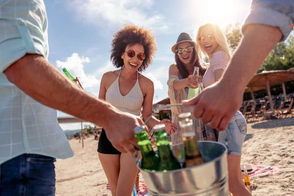 Cheerful friends enjoying weekend and having fun on the beach, drinking beer