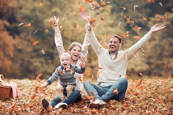昼間の公園で秋を投げる楽しみの葉幸せな家族を持つ — ストック写真