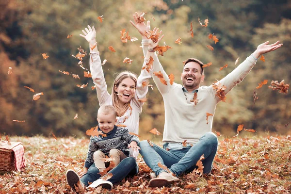 昼間の公園で秋を投げる楽しみの葉幸せな家族を持つ — ストック写真