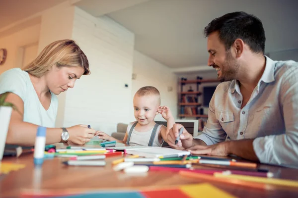 Mom and dad drawing with their son.They are  having fun in their living room.