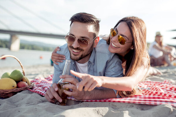 Portrait of happy couple on the beach, girl showing something to her boyfriend.