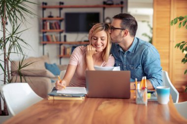 Onlar oturma odası ve oynamak için dizüstü bilgisayar kullanarak masada oturan çift faturaları.