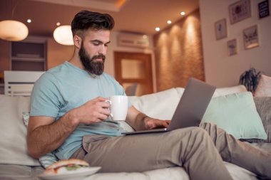 Laptop ile evde çalışırken içme kahve yakışıklı genç adam