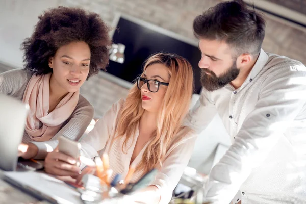 Dizüstü bilgisayar, çalışma iş ortakları cep telefonu arıyorum. Modern ofisinde çalışan genç iş adamları.