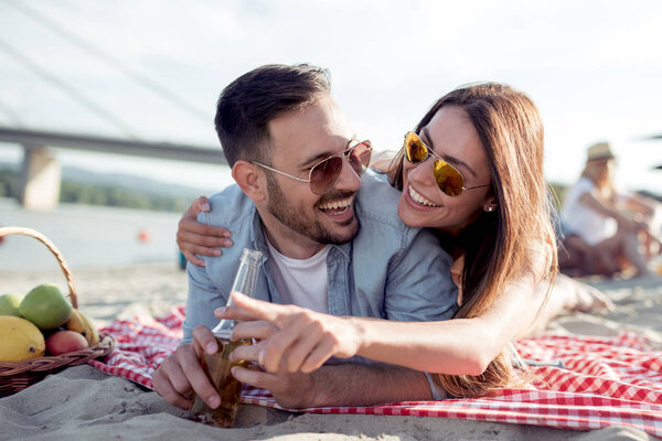 Portrait of happy couple on the beach,girl showing something to her boyfriend.
