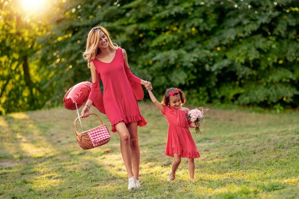 公園を一緒に歩いて赤い服に身を包んだ美しい母と娘 — ストック写真
