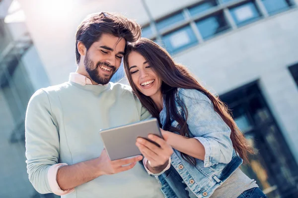 Park bankında oturan ve having fun tablet ile genç çift