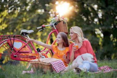 Anne ve kızı suyu içme ve bir bisiklet sürme sonra piknik 