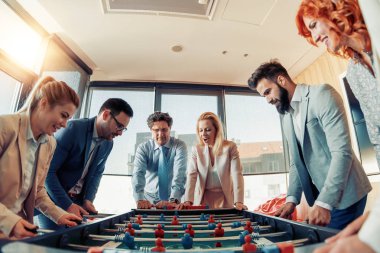 Modern ofis futbol oynarken gülümseyen iş arkadaşları.