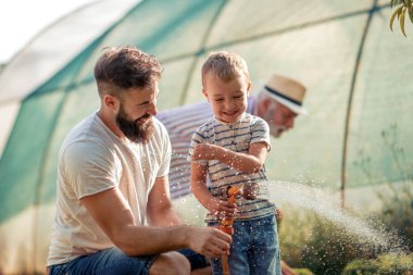 Oğluyla eğleniyor ve bahçede çalışan genç baba