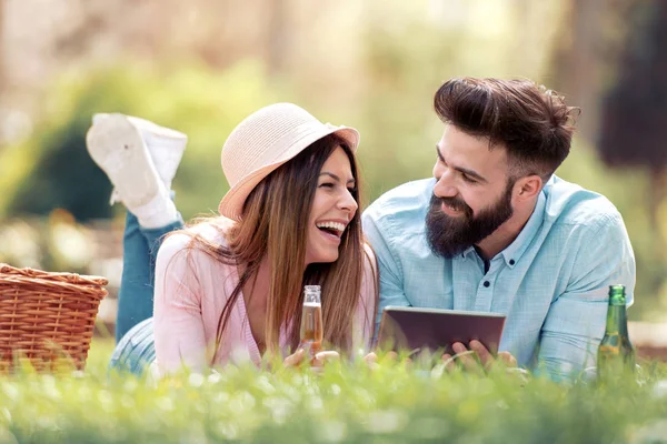 Pareja Cariñosa Picnic Parque Bebiendo Cerveza Sosteniendo Tableta — Foto de Stock