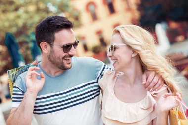 güzel mutlu çift alışveriş sonra alışveriş torbaları ile gülümseyen ve gün ışığında sarılma şehirde