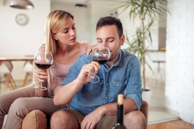Oturma odasında kanepede oturan ve şarap içme genç romantik çift