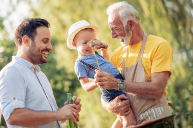 Mutlu bir aile barbekü yemek bahçede güneşli günde.