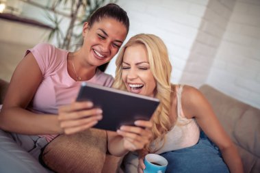 Evde tablet kullanan mutlu genç bayan arkadaşlar..