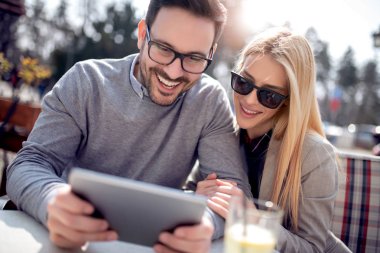 Teknoloji, freelancing, sevgi ve insan kavramı. Genç adam bir şey onun güzel kız tablet için gösterir.