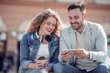 Şehir Parkı içinde smartphone kullanarak kulaklık ile güzel genç çift.