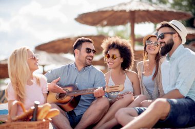 Mutlu arkadaş rahatlatıcı ve sahilde gitar çalmak. Beach partide eğleniyor .