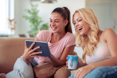 Evde tablet kullanan mutlu genç bayan arkadaşlar..