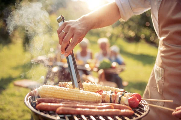 Człowiek Grillowaniu Potraw Pierwszym Planie Podczas Gdy Osoby Posiadające Grill — Zdjęcie stockowe